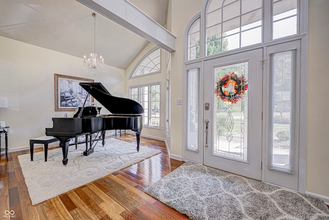 entrance foyer with hardwood / wood-style flooring, plenty of natural light, a notable chandelier, and vaulted ceiling