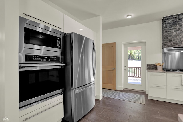 kitchen featuring white cabinets, stainless steel appliances, and dark tile patterned floors