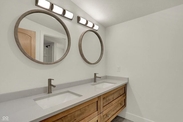 bathroom with a textured ceiling, vanity, and vaulted ceiling