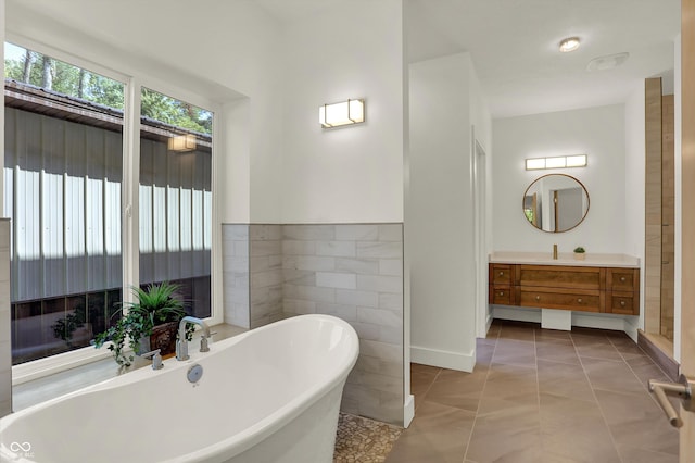 bathroom featuring tile walls, tile patterned flooring, a bathing tub, and vanity