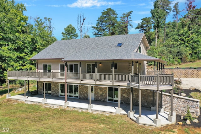 rear view of house with a yard, a wooden deck, and a patio