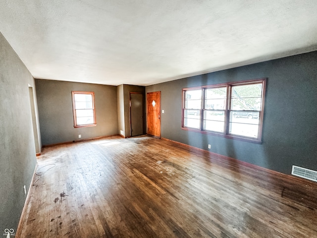 unfurnished room featuring a wealth of natural light, hardwood / wood-style flooring, and a textured ceiling