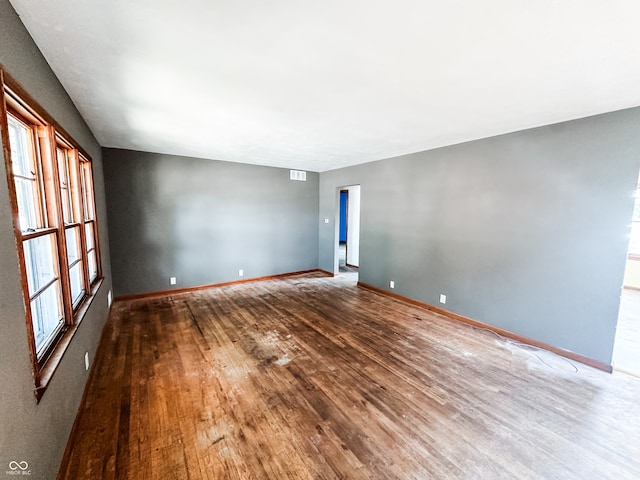 empty room with a healthy amount of sunlight and hardwood / wood-style floors