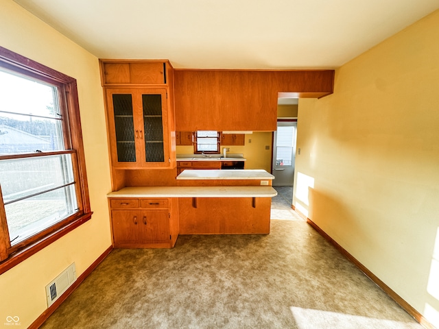 kitchen with kitchen peninsula, sink, and light colored carpet