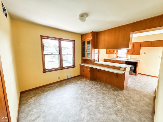 kitchen featuring a breakfast bar, kitchen peninsula, beverage cooler, and light carpet