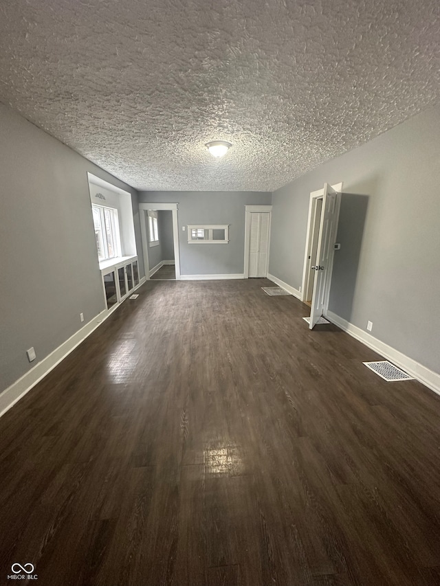 interior space with a textured ceiling and dark hardwood / wood-style floors