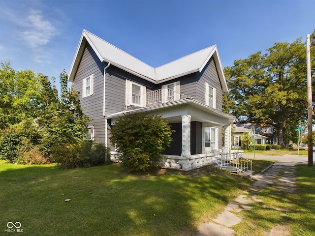 view of side of home with a lawn, covered porch, and a balcony