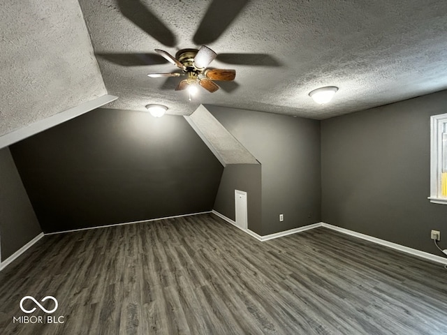 bonus room featuring a textured ceiling, ceiling fan, dark hardwood / wood-style flooring, and lofted ceiling