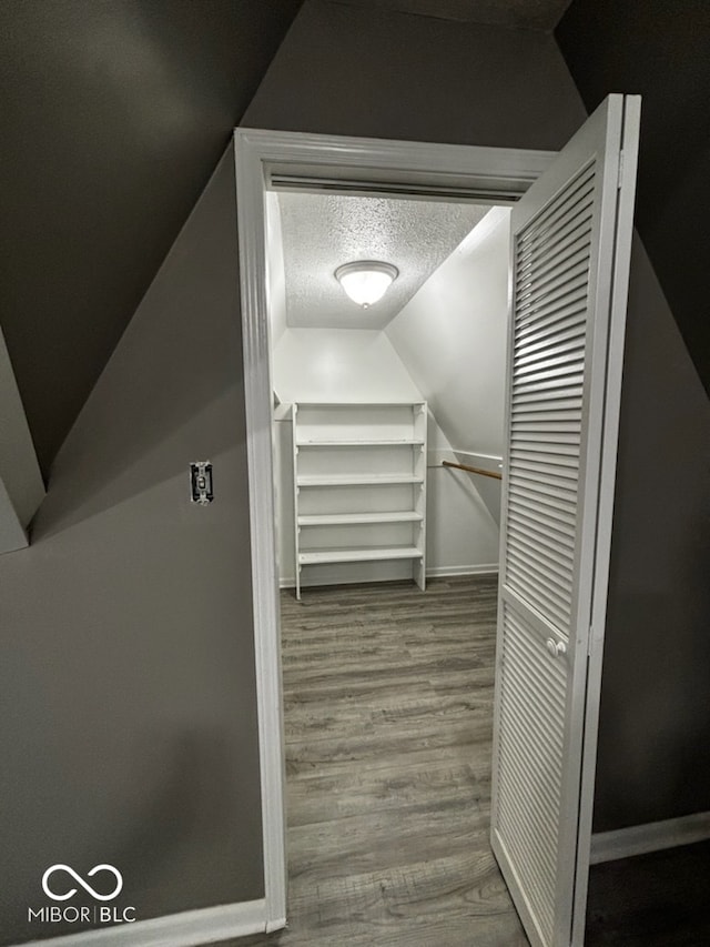 spacious closet with hardwood / wood-style flooring and vaulted ceiling