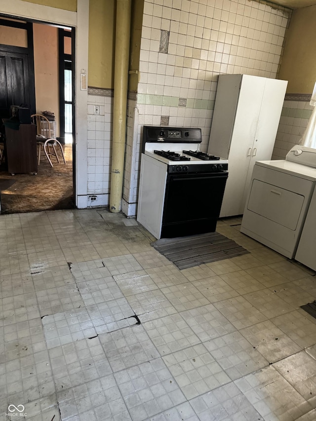 1804 N Delaware St, Indianapolis, IN 46202 - kitchen featuring washer / dryer, gas stove, tile walls, and light flooring