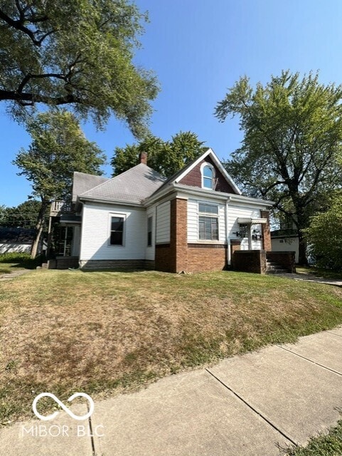 view of side of property featuring a yard, brick siding, and a chimney