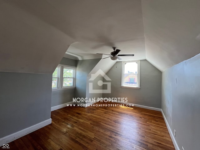 additional living space with dark wood-type flooring, vaulted ceiling, a wealth of natural light, and ceiling fan