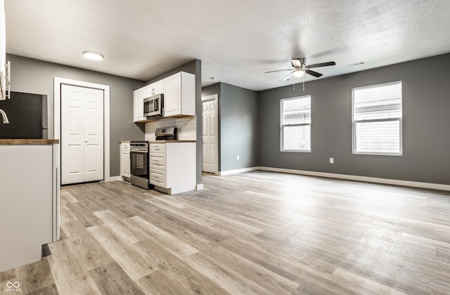 kitchen featuring appliances with stainless steel finishes, light hardwood / wood-style floors, white cabinetry, and ceiling fan