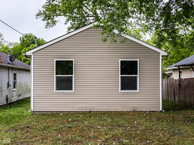 view of side of home featuring fence and a yard