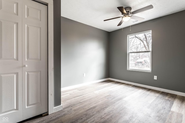 unfurnished room with wood finished floors, visible vents, and baseboards