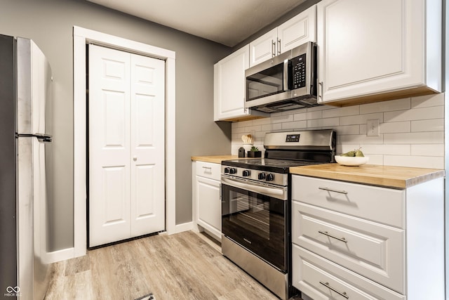 kitchen featuring light wood finished floors, white cabinets, butcher block counters, stainless steel appliances, and backsplash