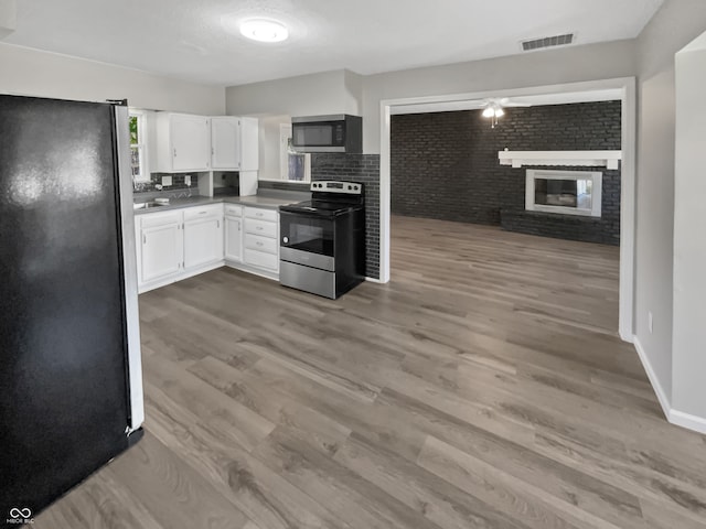 kitchen featuring a fireplace, hardwood / wood-style floors, tasteful backsplash, stainless steel appliances, and white cabinets