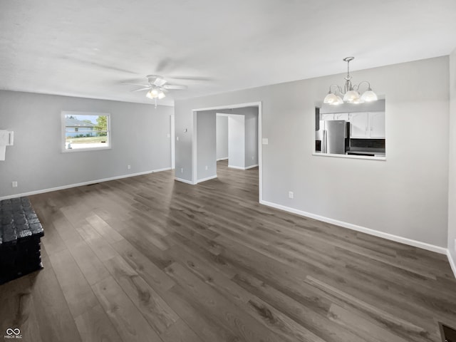 unfurnished living room with ceiling fan with notable chandelier and dark wood-type flooring