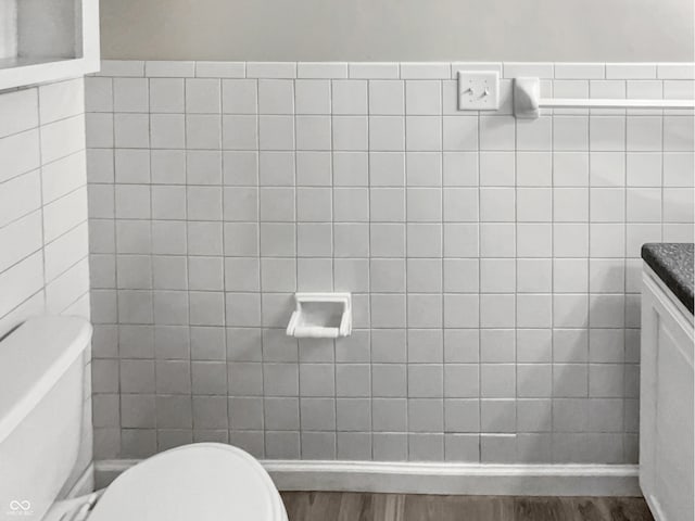 bathroom with tile walls, wood-type flooring, toilet, and vanity