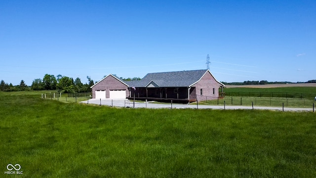 exterior space featuring a lawn, an outdoor structure, a rural view, and a garage