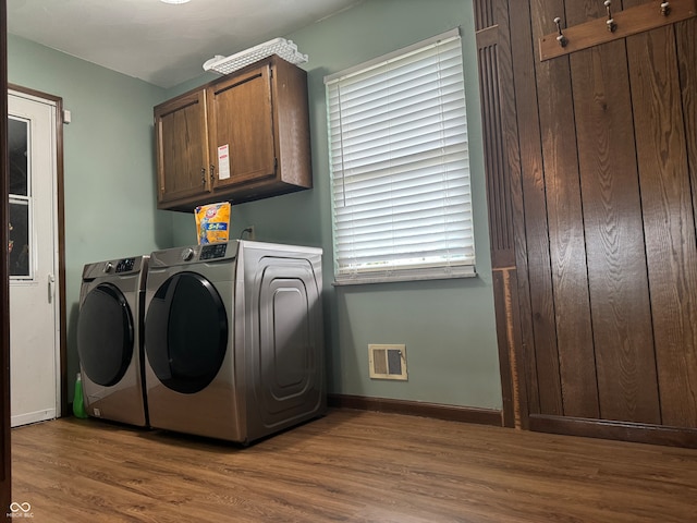 washroom featuring cabinets, hardwood / wood-style floors, and washing machine and dryer