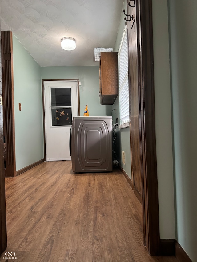 washroom featuring washer / dryer, hardwood / wood-style floors, and cabinets