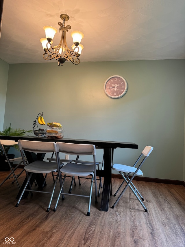 dining room with wood-type flooring and an inviting chandelier