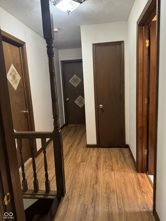 hallway with a textured ceiling and light wood-type flooring