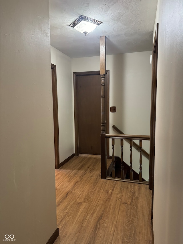 corridor with a textured ceiling and light hardwood / wood-style floors