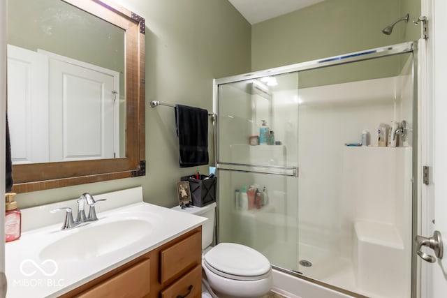 bathroom featuring a shower with shower door, toilet, and vanity