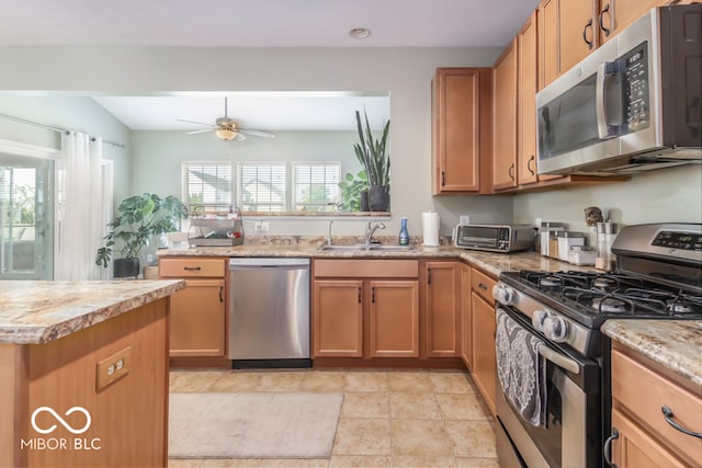 kitchen with appliances with stainless steel finishes, sink, light tile patterned flooring, and ceiling fan