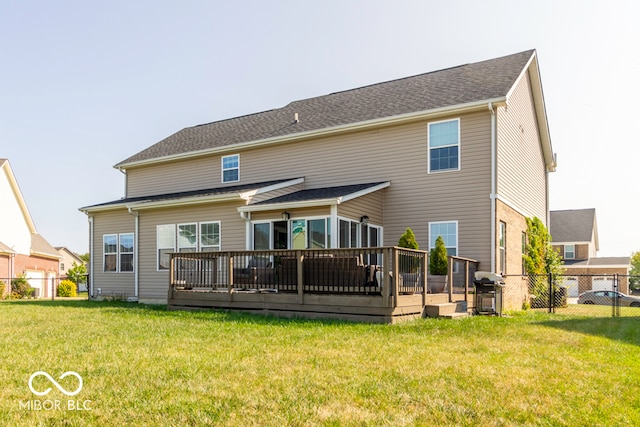 rear view of house featuring a wooden deck and a lawn