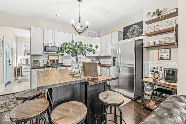 kitchen featuring tasteful backsplash, butcher block countertops, white cabinetry, and stainless steel appliances