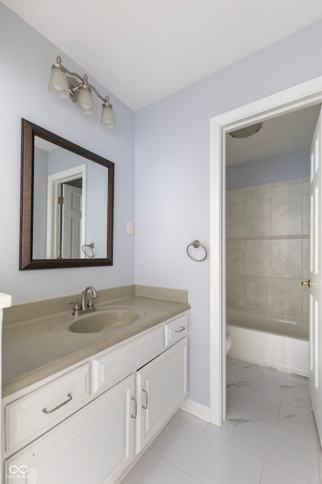 full bathroom featuring tiled shower / bath combo, vanity, and toilet