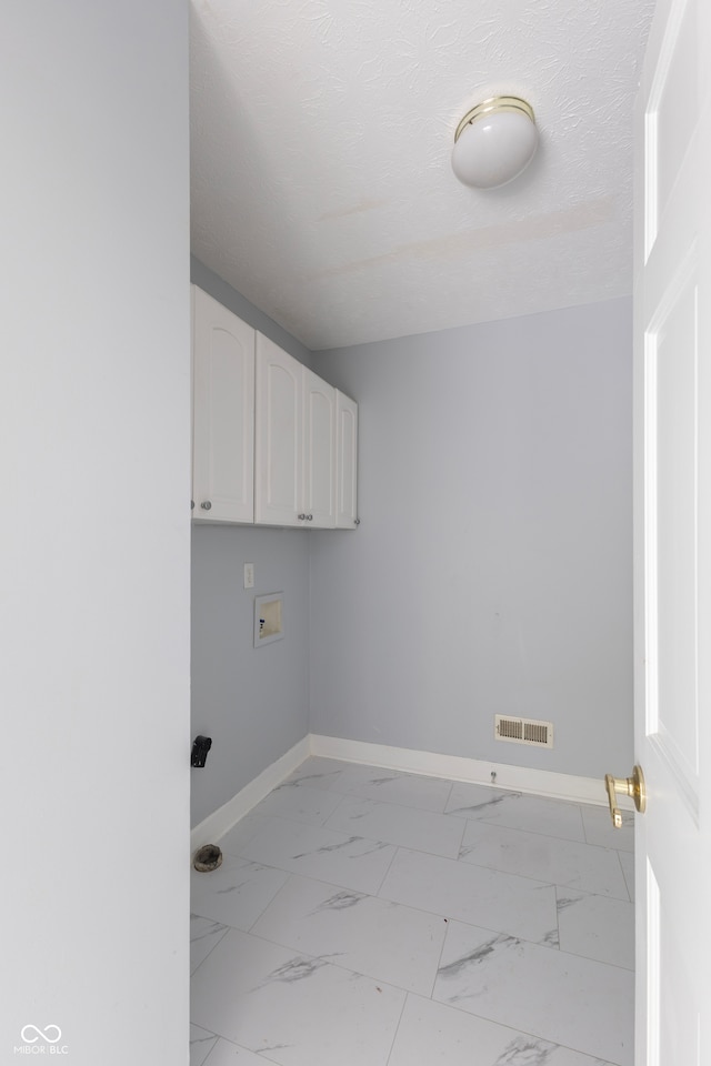 washroom featuring a textured ceiling, cabinets, and hookup for a washing machine