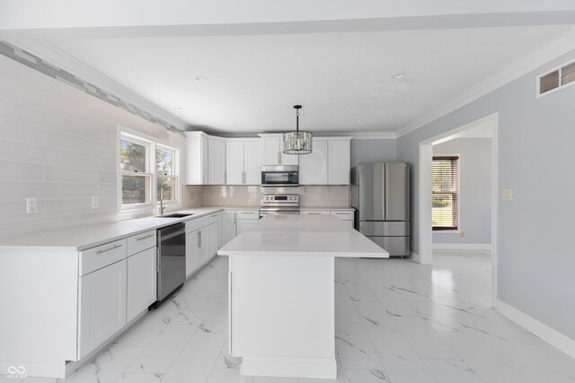 kitchen with appliances with stainless steel finishes, tasteful backsplash, a kitchen island, and pendant lighting