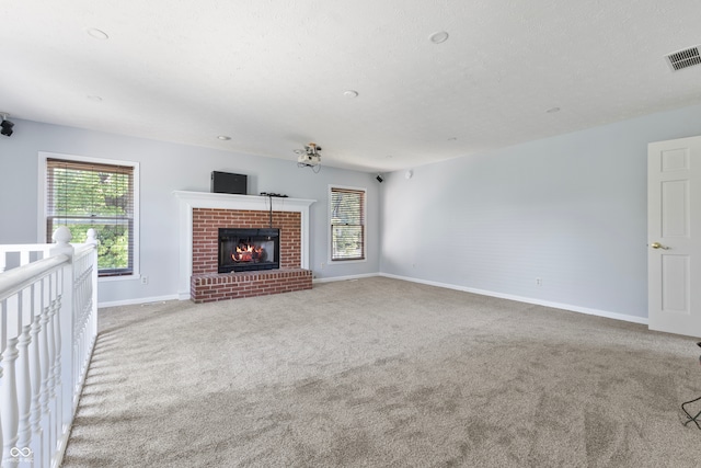 unfurnished living room featuring a textured ceiling, light colored carpet, and a fireplace