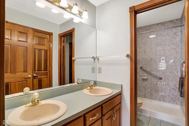 bathroom with vanity, toilet, tiled shower, and tile patterned floors