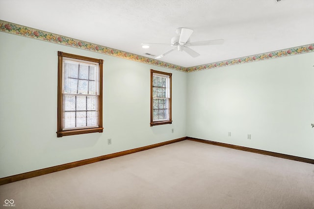 carpeted spare room featuring a textured ceiling, plenty of natural light, and ceiling fan