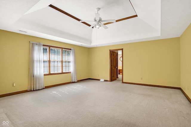 spare room with a tray ceiling, ceiling fan, and light colored carpet