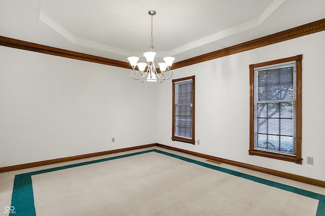 carpeted empty room with a raised ceiling and a chandelier