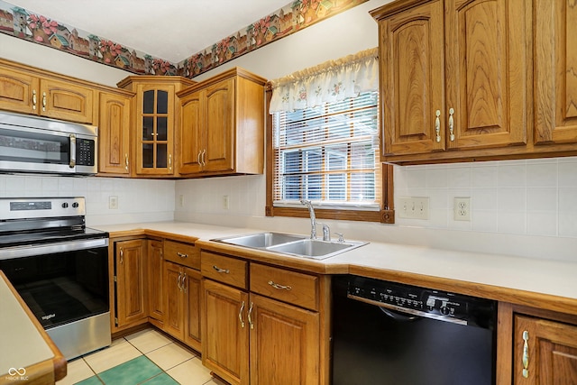 kitchen featuring stainless steel appliances, sink, light tile patterned floors, and tasteful backsplash