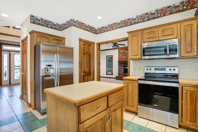 kitchen with a kitchen island, ceiling fan, appliances with stainless steel finishes, and light tile patterned flooring