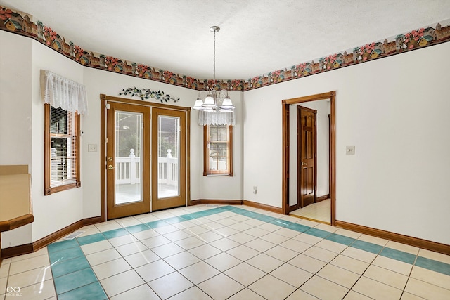 tiled spare room with french doors, a textured ceiling, and a chandelier