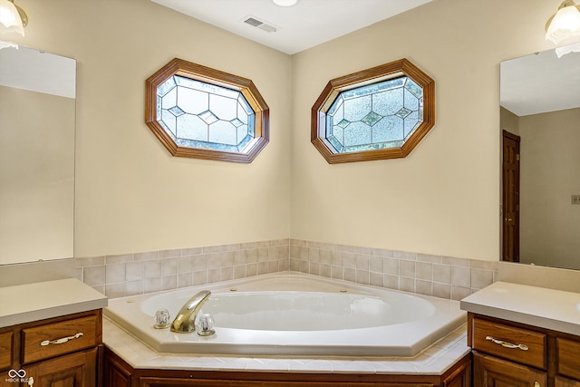 bathroom featuring tiled tub and vanity