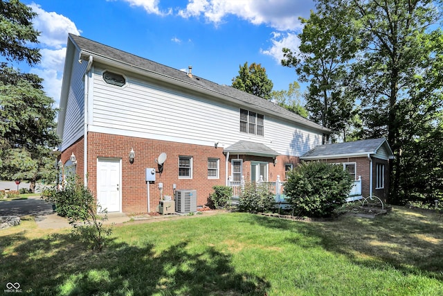 rear view of house with a garage, a yard, and cooling unit