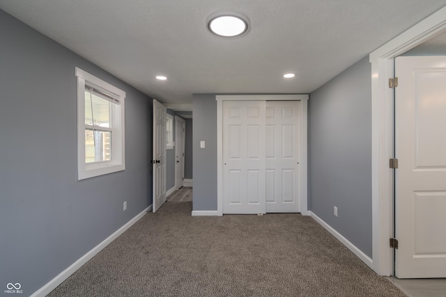 unfurnished bedroom featuring recessed lighting, a closet, baseboards, and carpet