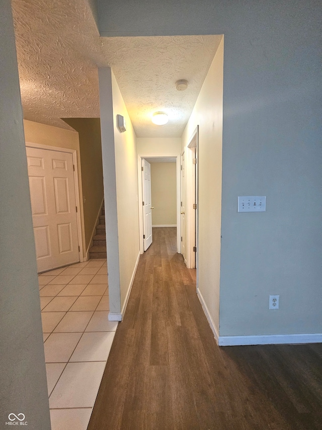 corridor with a textured ceiling and light tile patterned floors