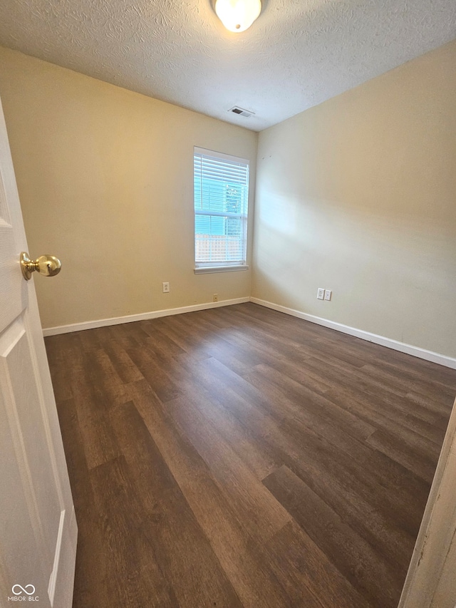 spare room with dark hardwood / wood-style floors and a textured ceiling