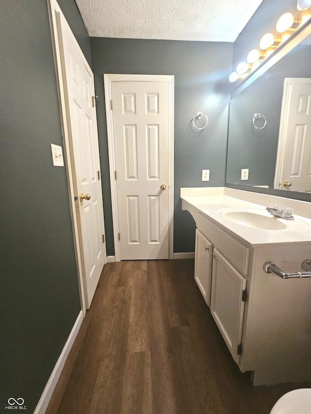 bathroom with hardwood / wood-style flooring, a textured ceiling, and vanity